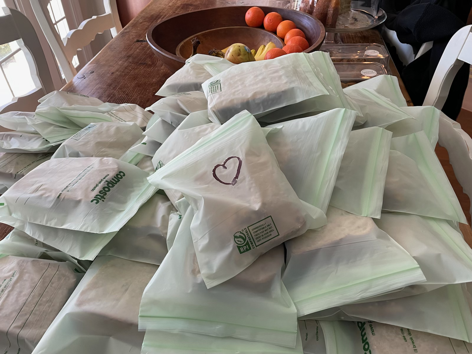Packaged sandwiches stacked on a dining table.